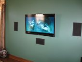 Tv mounted onto the wall with speakers installed around